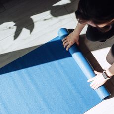 Hot pilates: A woman rolling out a workout mat