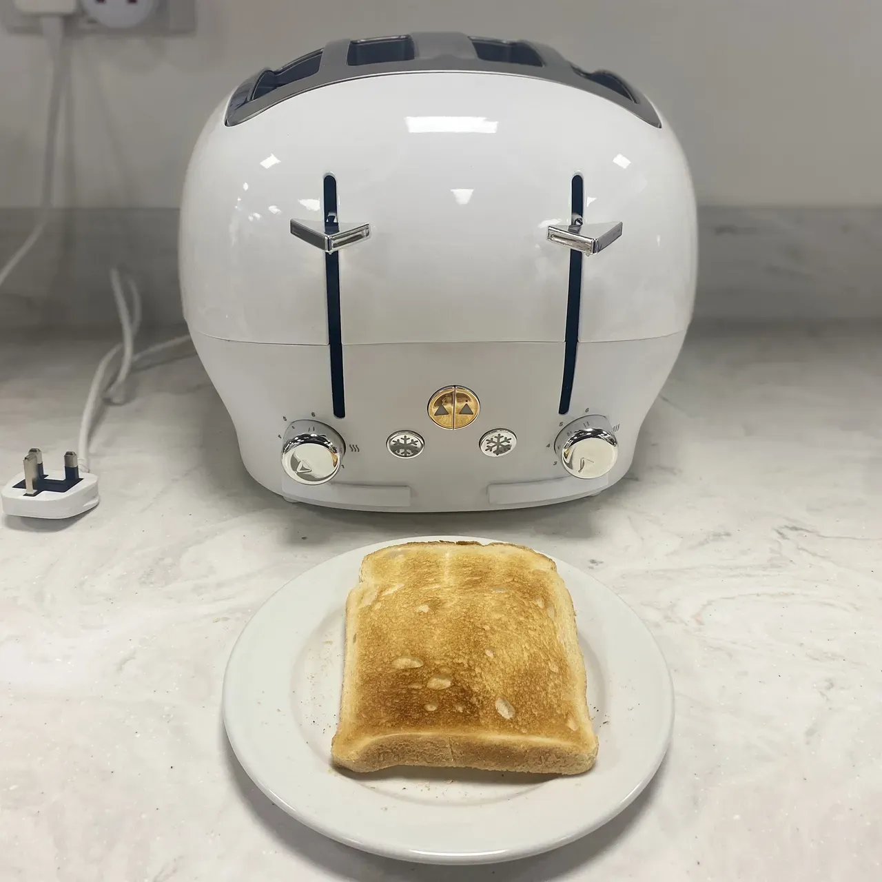 Testing a white toaster on a marble countertop at the test centre with a piece of toast also on table