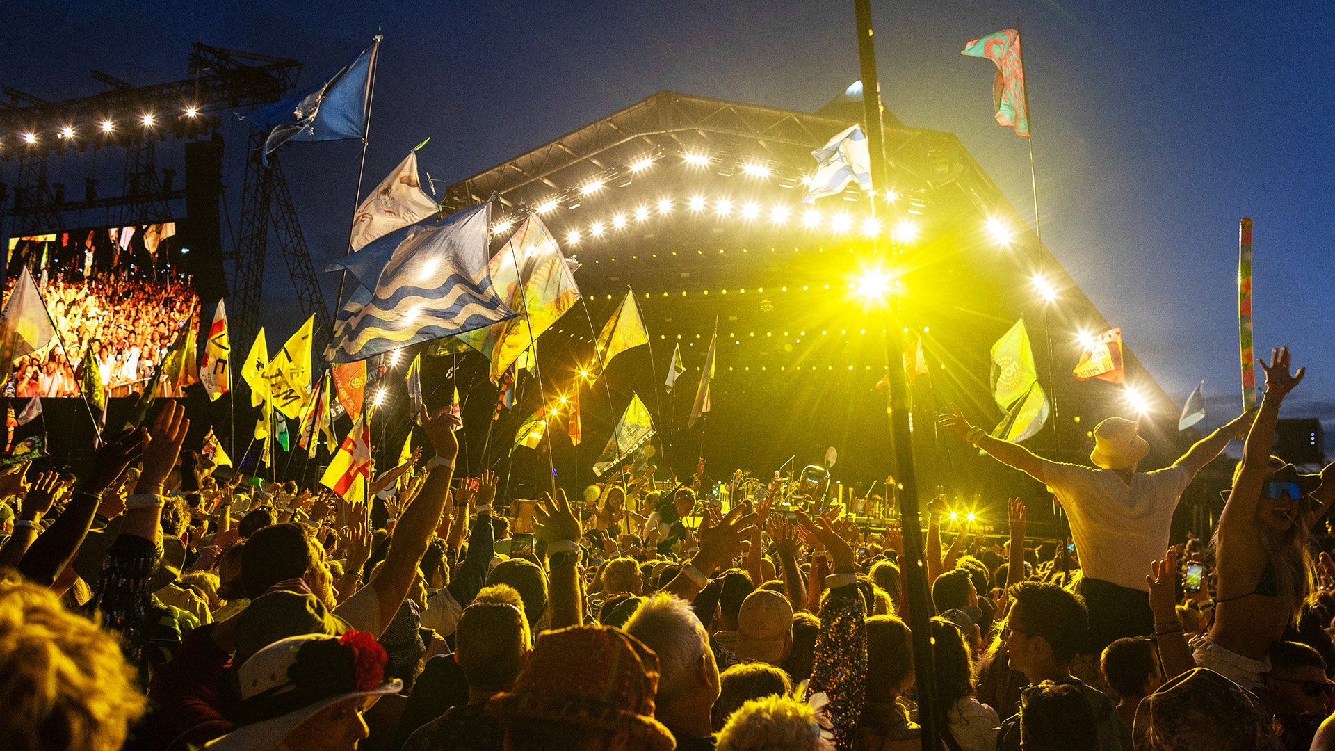 Pyramid stage at Glastonbury Festival 2024, lit up at night with crowd in foreground and Coldplay performing