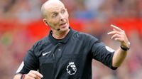 Former Premier League referee Mike Dean gesturing to a player during a game.