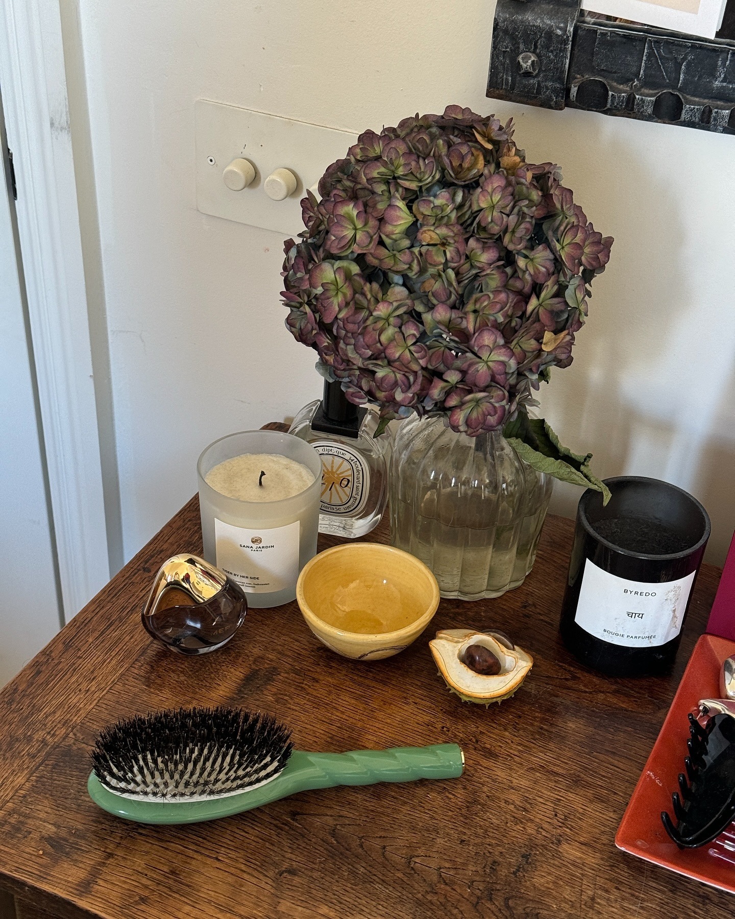 A wooden side table with candles, flowers and a hairbrush