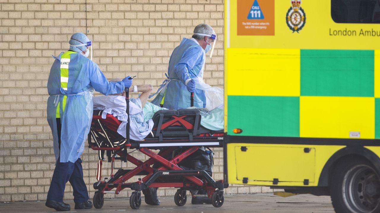 NHS workers in PPE transport a patient