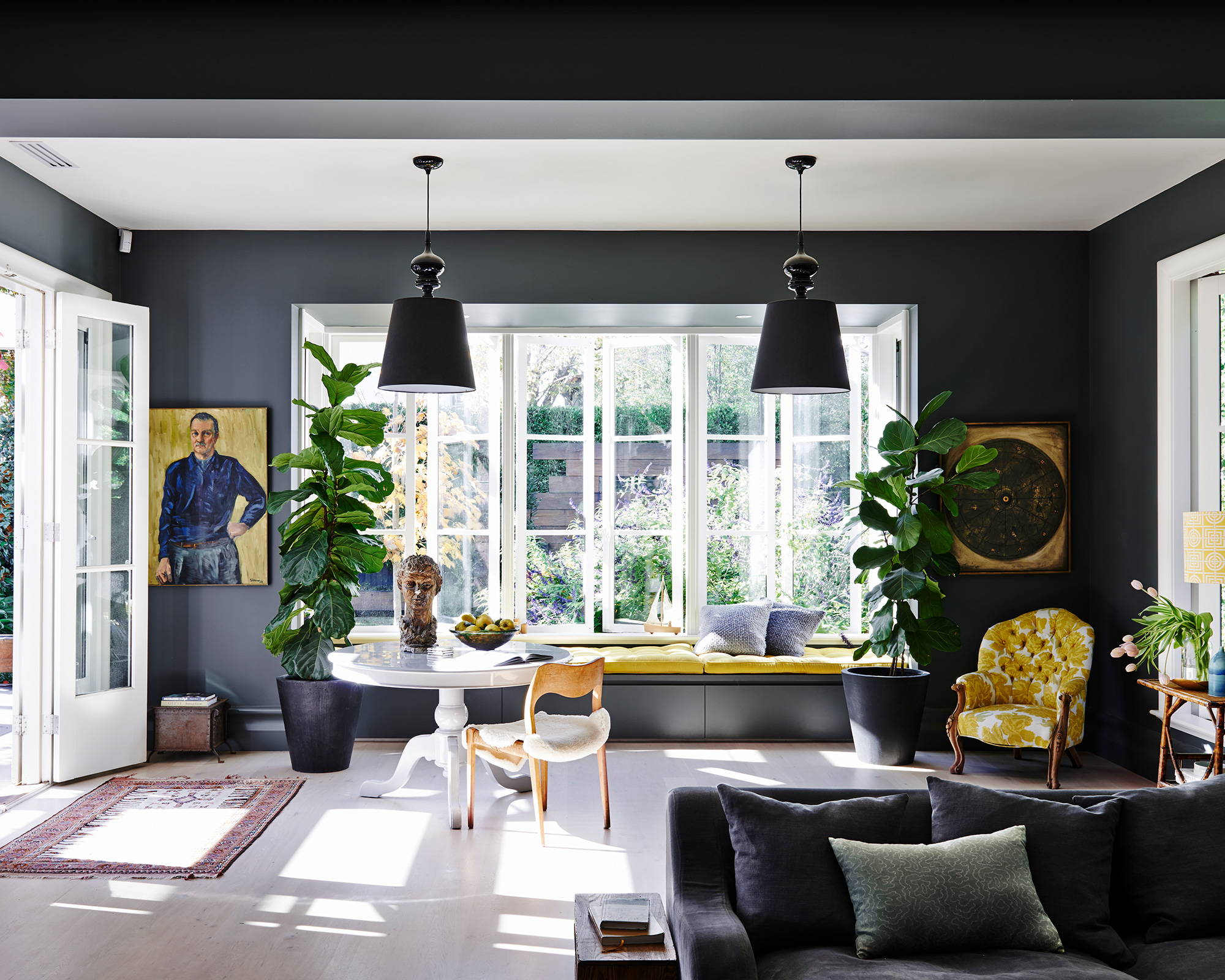 Dark grey living room ideas shown with mustard yellow accents and white flooring.
