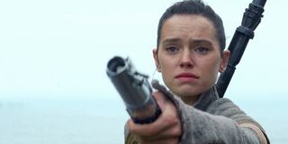 Rey holding out a lightsaber to Luke Skywalker