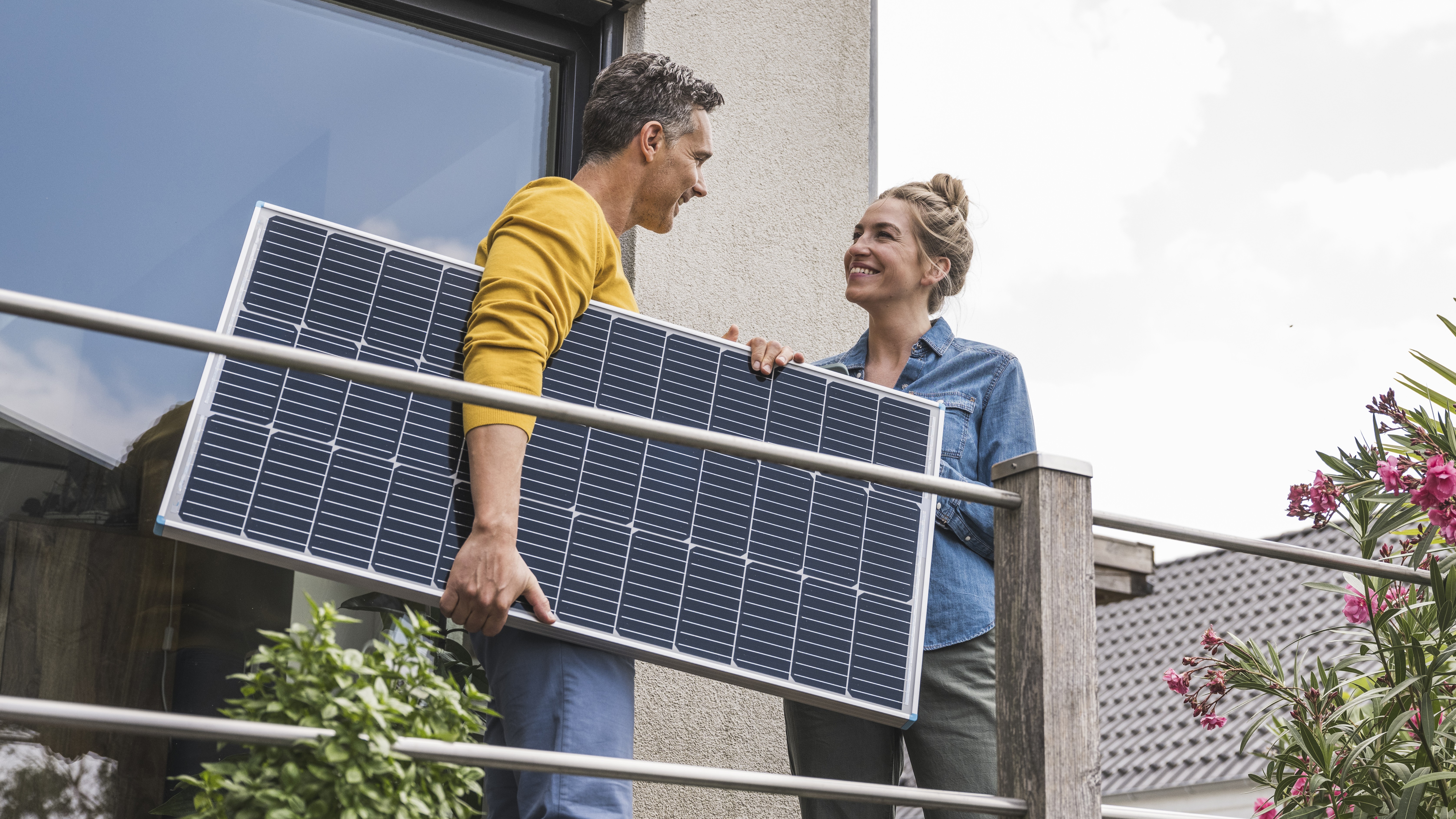 Couple standing on balcony holding solar panel