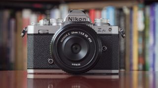 The Nikon Zfc, one of the best camera for beginners, sitting on a red table in front of a book case