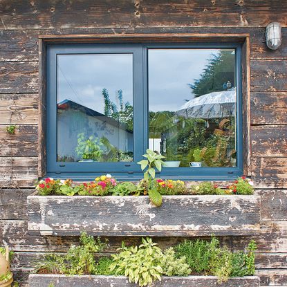 distressed wood of exterior of house with graphite window frame and window boxes