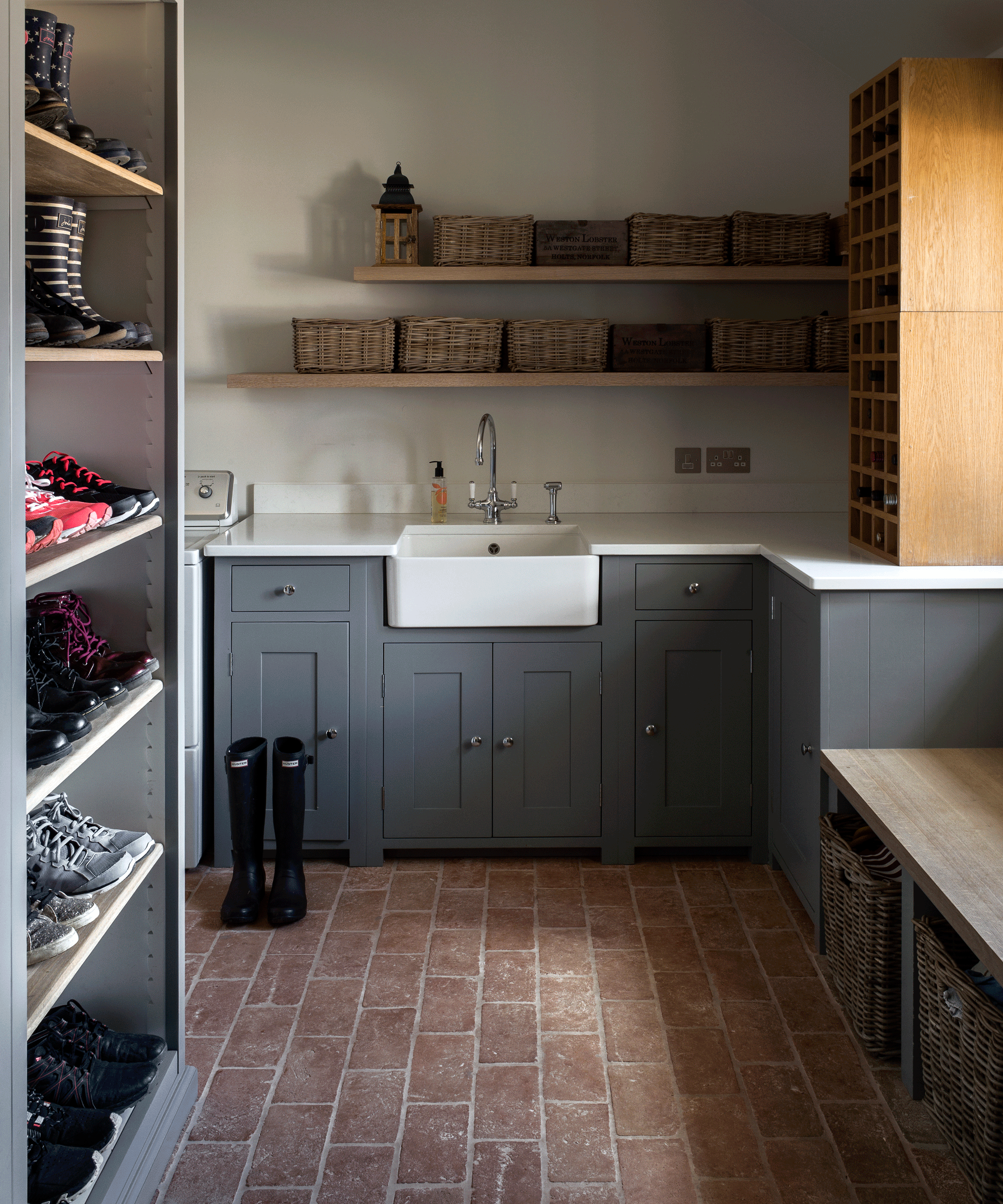 Utility room with grey cabinetry, shoe storage and brick flooring