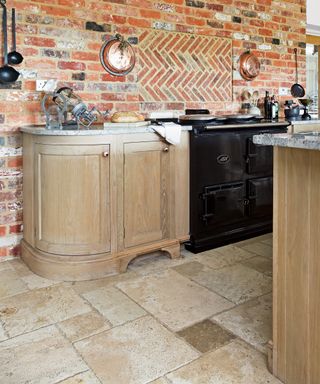 Wood kitchen with exposed brick wall and travertine tiles