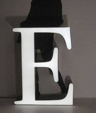 Letter "E", lit in white LED, in front of a woman's silhouette