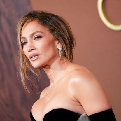 a latina woman with bronde hair posing in a gown on a red carpet