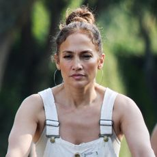 Jennifer Lopez wears a pair of white overalls and a high bun with oversize silver hoops on a bike ride in the Hamptons