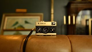 Rollei 35 Retrospekt 24K Gold Edition camera on a leather sofa in a luxury home