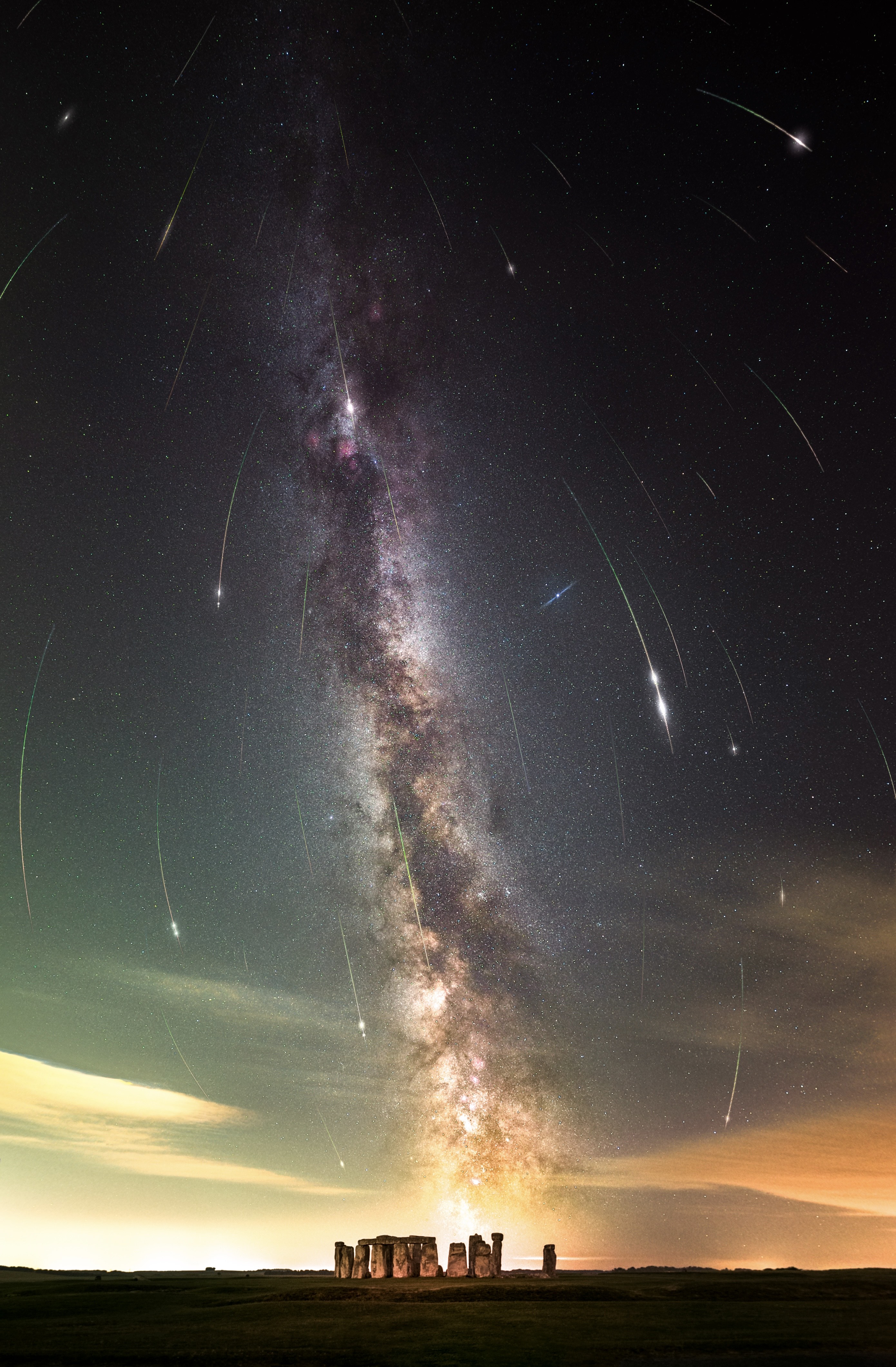 The stone arrangements are at the base of the image and the Milky Way stretches vertically across the sky above while the Perseids appear to rain down on the sky in long streaks of light.