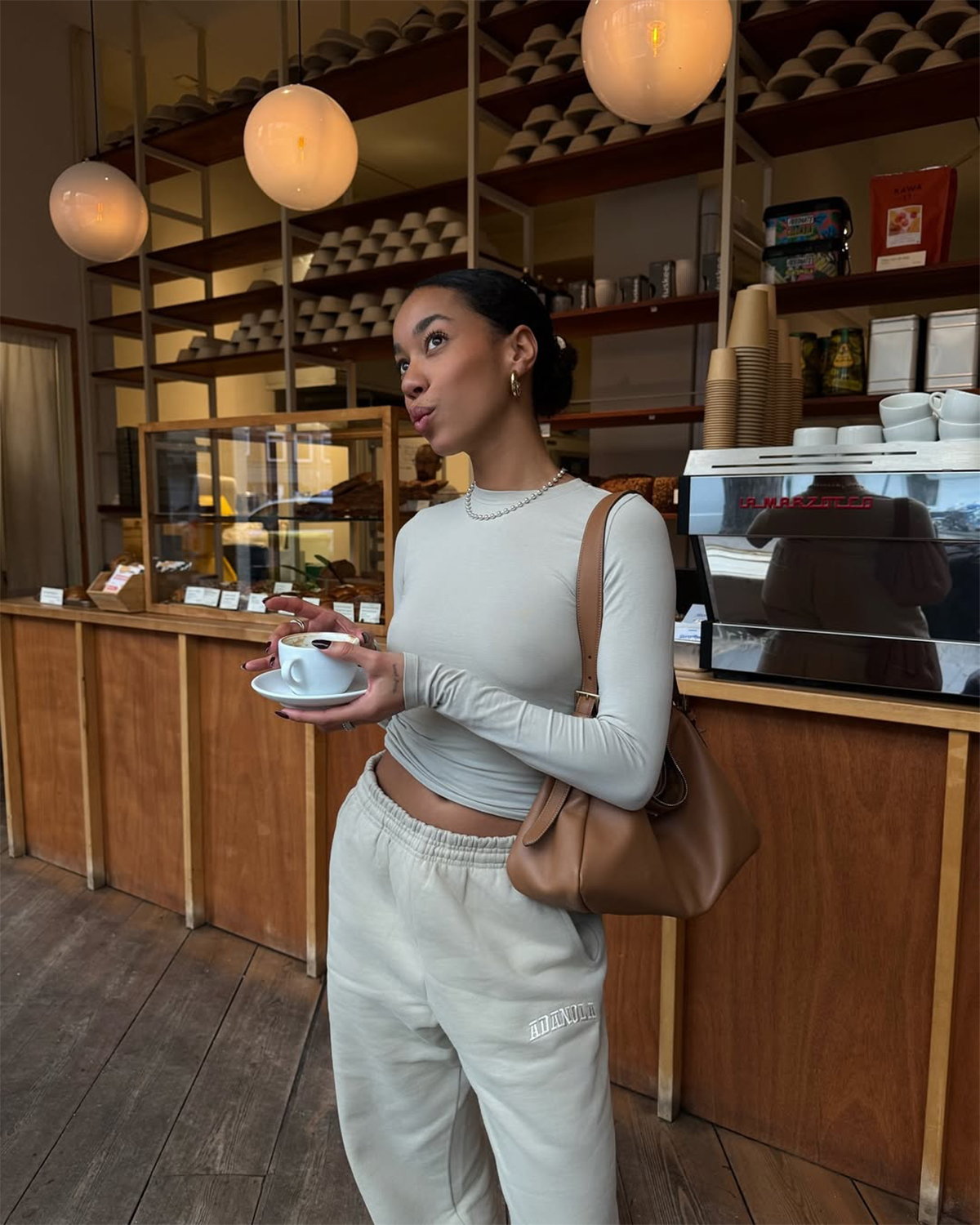 Amaka Hamelijnck pictured in a coffee shop with a slicked back bun and glowing skin