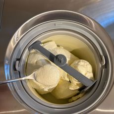 Stainless steel Cuisinart ice cream maker with a bowl filled with vanilla ice cream