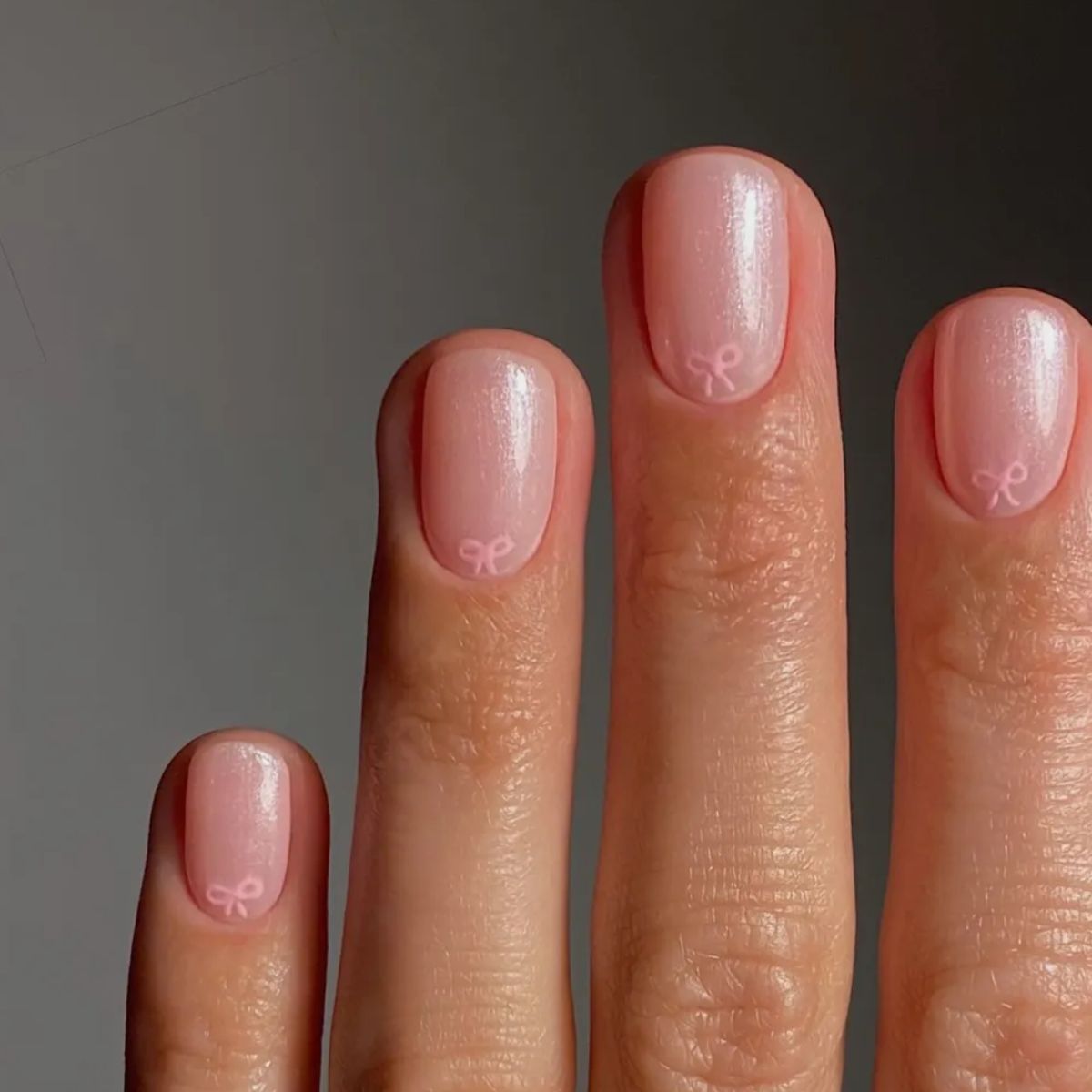 A chrome manicure with a pink bow design