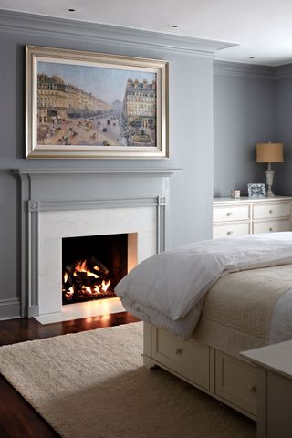 bedroom with fire lit and painting above concealing wallmounted TV