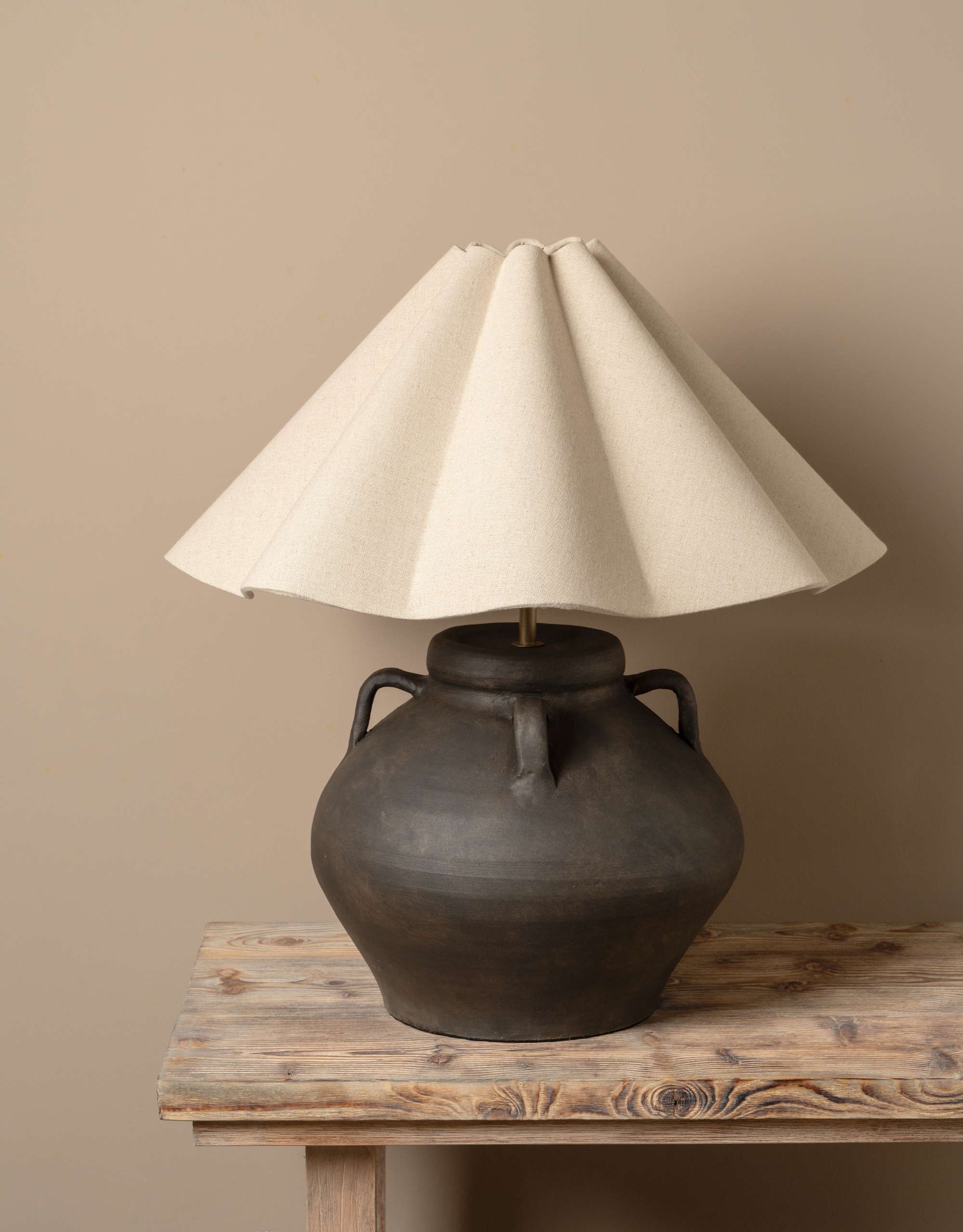 An oversized table lamp with a dark earthenware softly rounded base and a pleated shade from lights&amp;amp;lamps