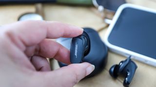 Henkilö pitää kädessään Bose QuietComfort Earbuds 2 -kuuloketta