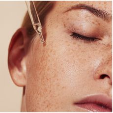 a close up of a woman using a pipette on her skin
