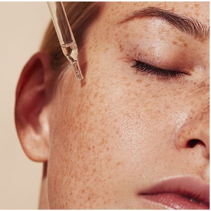 a close up of a woman using a pipette on her skin