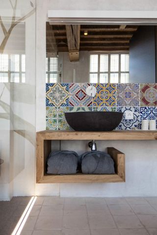 brightly coloured Portuguese inspired tiles in batrhoom with sink and freestanding unit