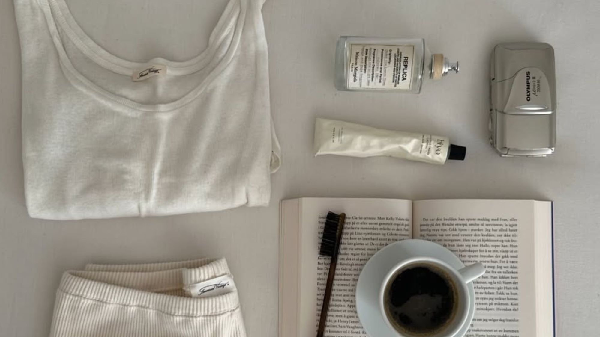 A flatlay image of products on a table, including a Maison Margiela Replica scent.