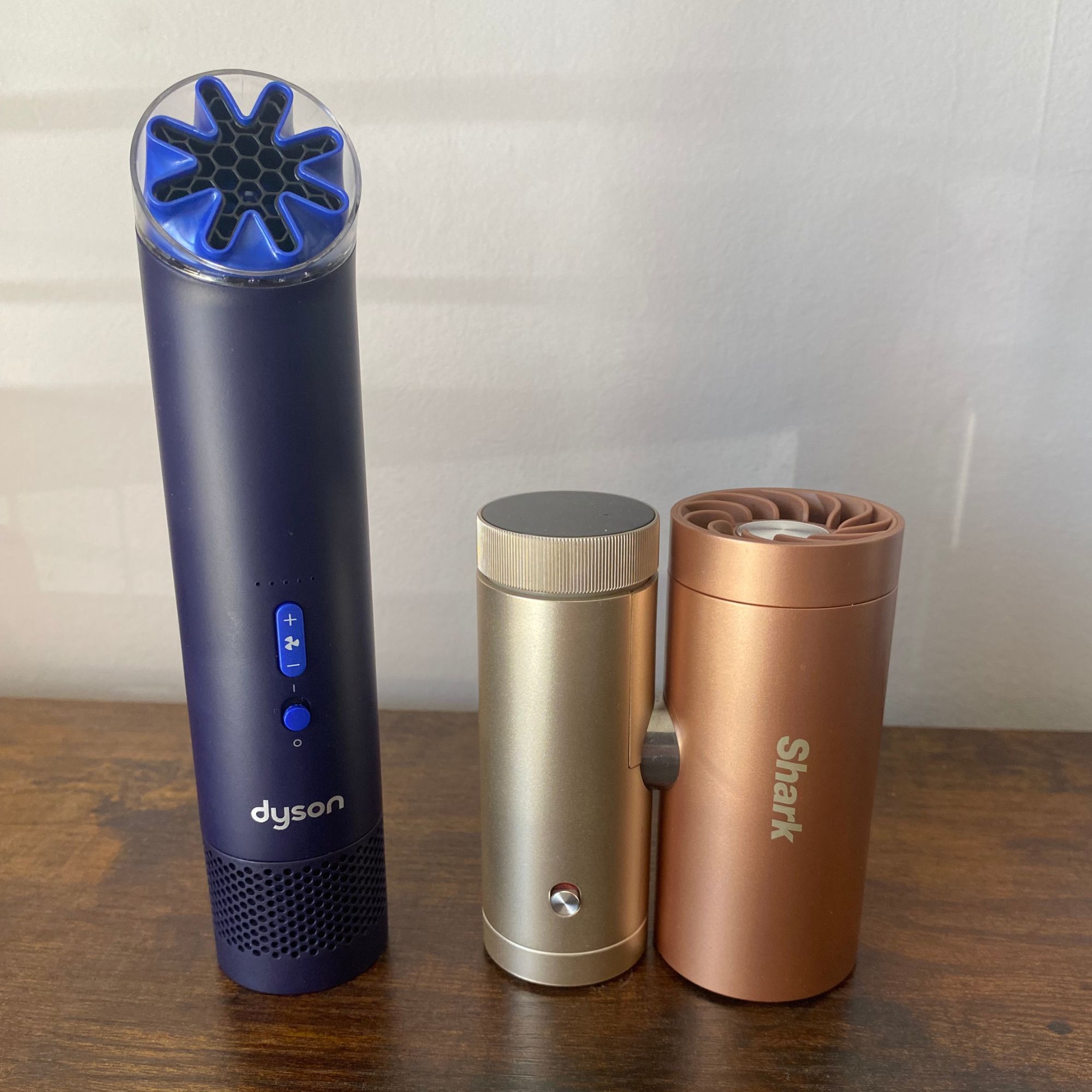 Dyson HushJet Mini Cool Fan on a wooden surface next to the Shark ChillPill