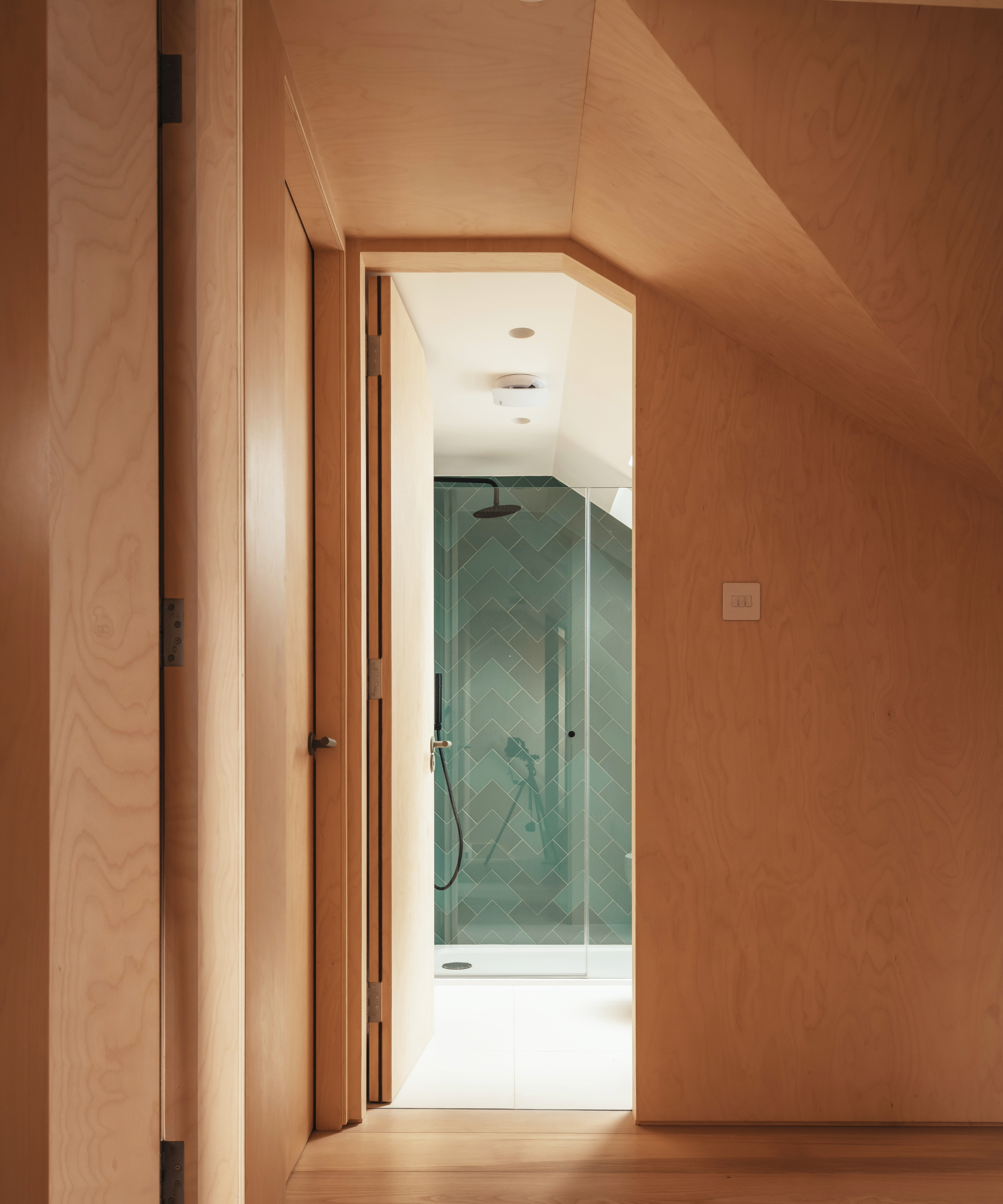 Hallway with views into a shower room with green tiles in the enclosure