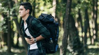 Young man hiking with stomach ache
