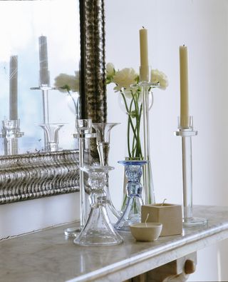 group of glass candlesticks in front of mirror on mantelpiece