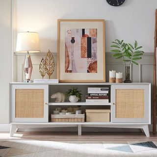 A rattan and wood TV stand console table with artwork sitting on top