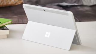 Microsoft Surface Go 2 on a white coffee table next to a stack of books