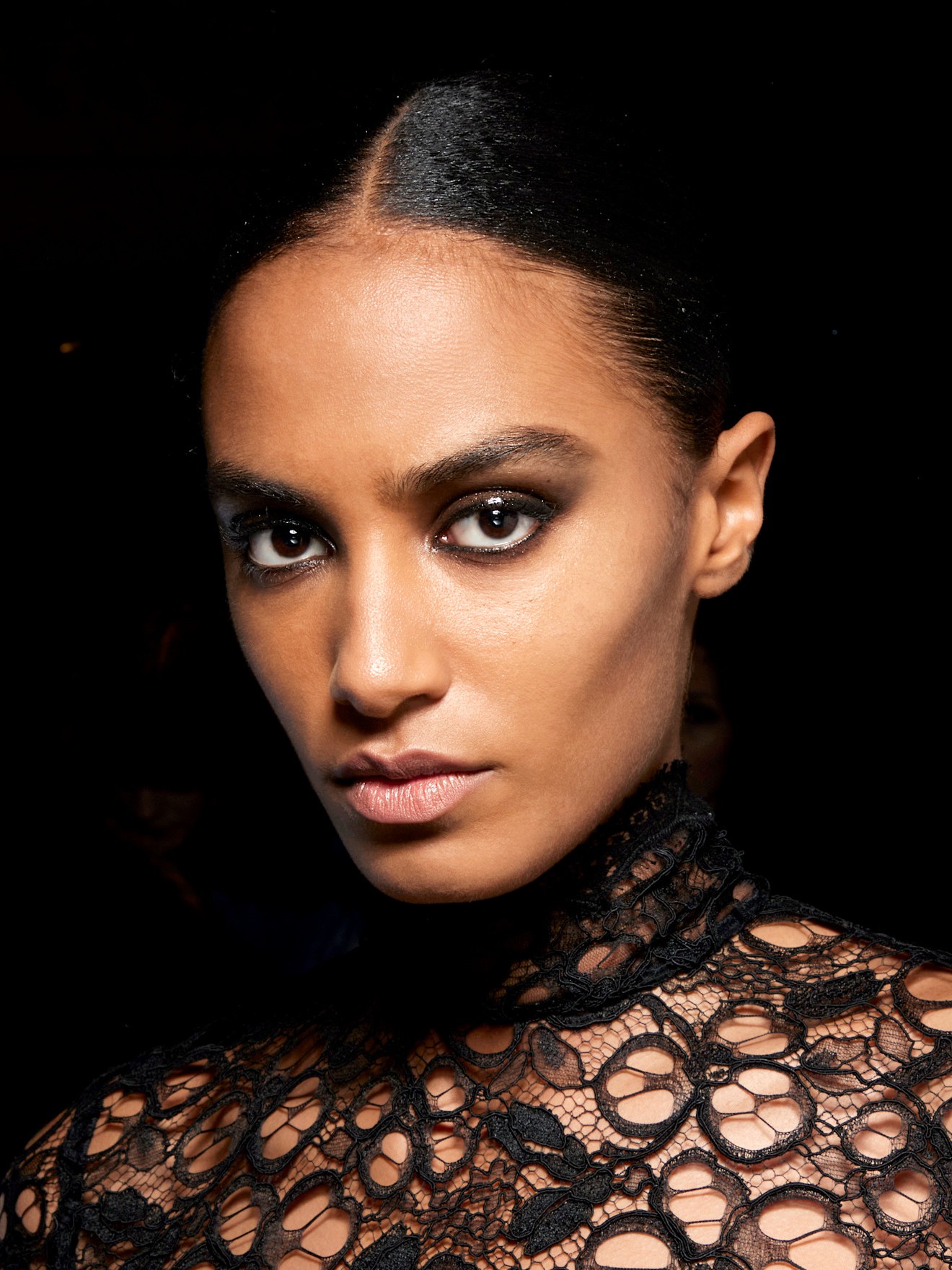 A model wearing a black lace top with black eyeliner