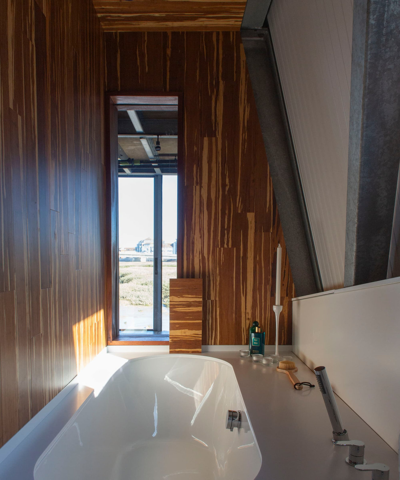 A white bath inside a steel structure house and wooden walls