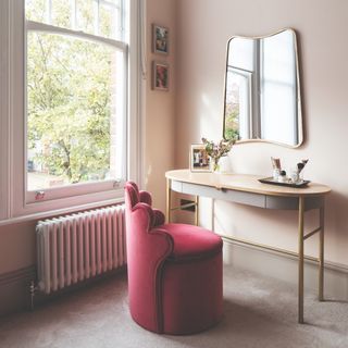 Vanity with pink velvet chair and a large window