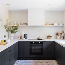 scandi style kitchen with white walls and worktops and dark painted cabinetry below