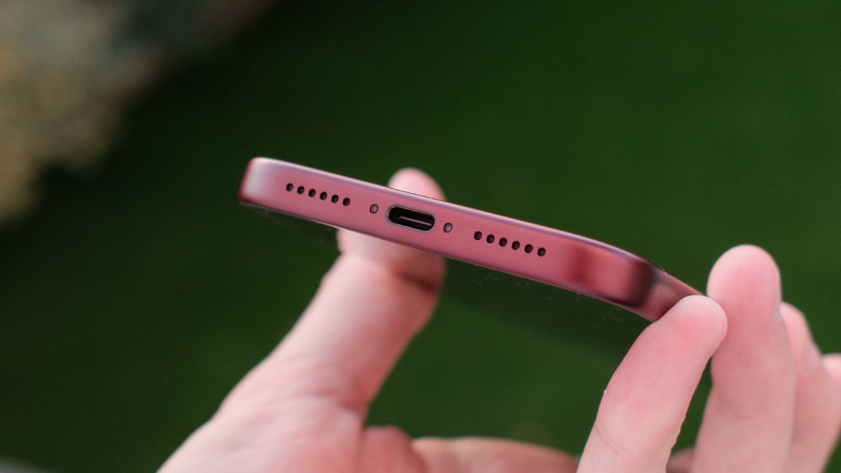 Close-up of the bottom edge of a burgundy iPhone 18 Pro Max showing the USB-C port and speaker grilles.