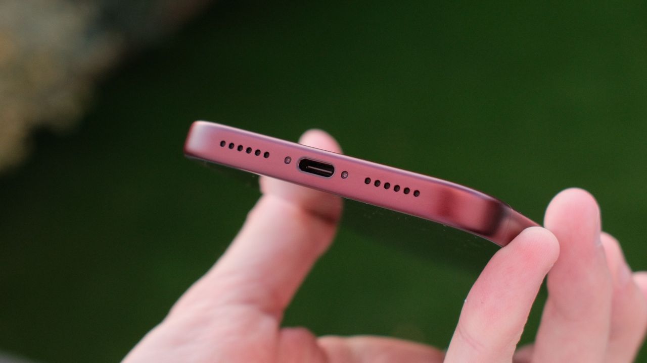 Close-up of the bottom edge of a burgundy iPhone 18 Pro Max showing the USB-C port and speaker grilles.