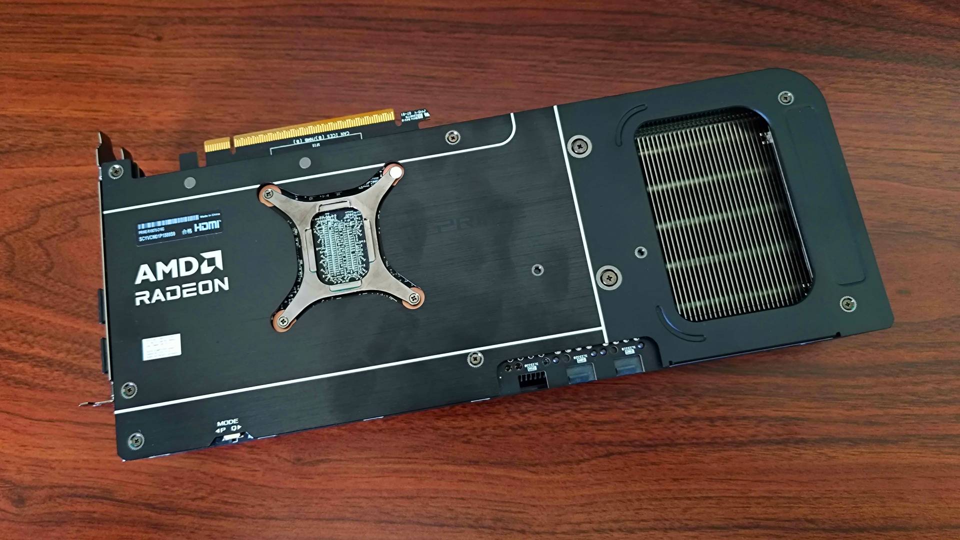 AMD Radeon RX 9070 Asus Prime graphics card on woodgrain desk with backplace facing upwards.