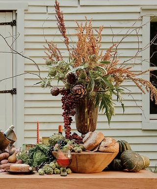 thanksgiving outdoor table with large fall foliage vase and pumpkins