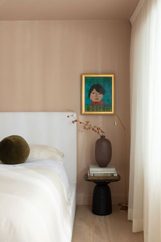 a bedroom painted in plaster pink with a colorful artwork on the wall