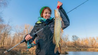 Woman holding a fish at the front of a lake