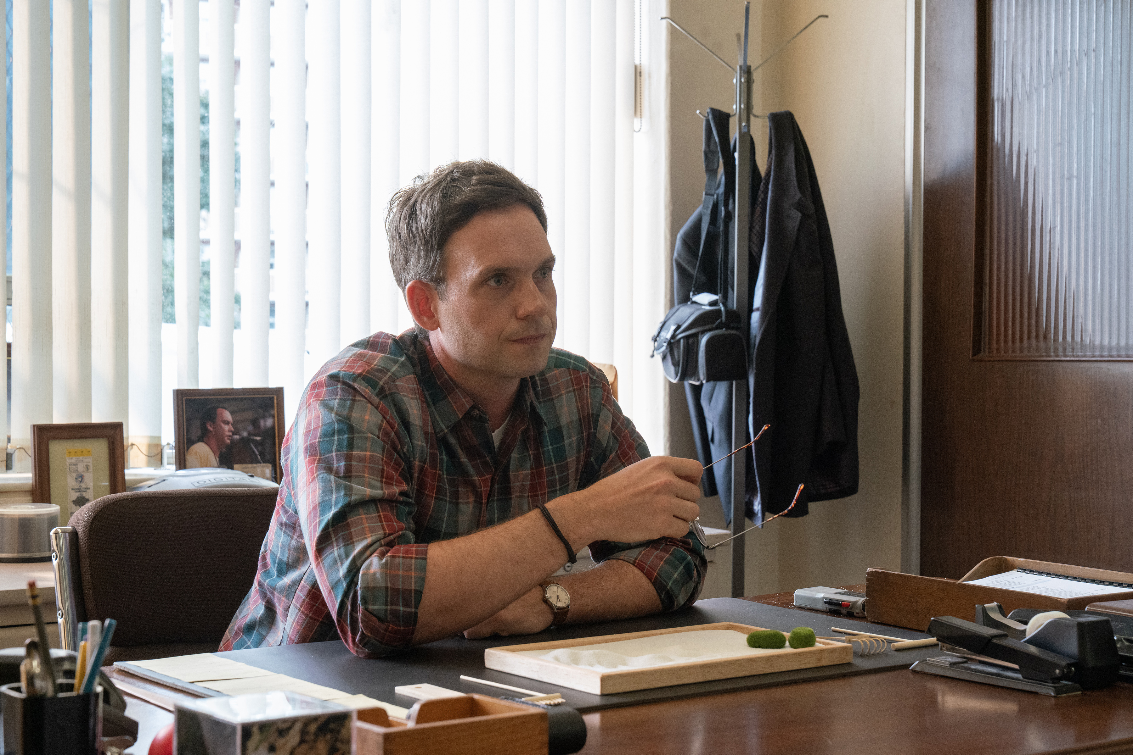 Patrick J. Adams as Mr. Turner sitting at a desk in an office in wayward