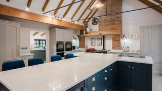 large kitchen with t shaped island, oak vaulted ceiling with view of back kitchen through door