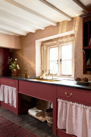 A red kitchen with sink skirts flanking either side of the sink