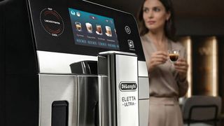Woman drinking espresso near De'Longhi Eletta Ultra coffee maker