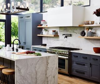 kitchen with blue units full height glazing marble topped island and backsplash