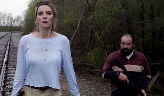 The Hunt Betty Gilpin and Ethan Suplee walk down the railroad armed